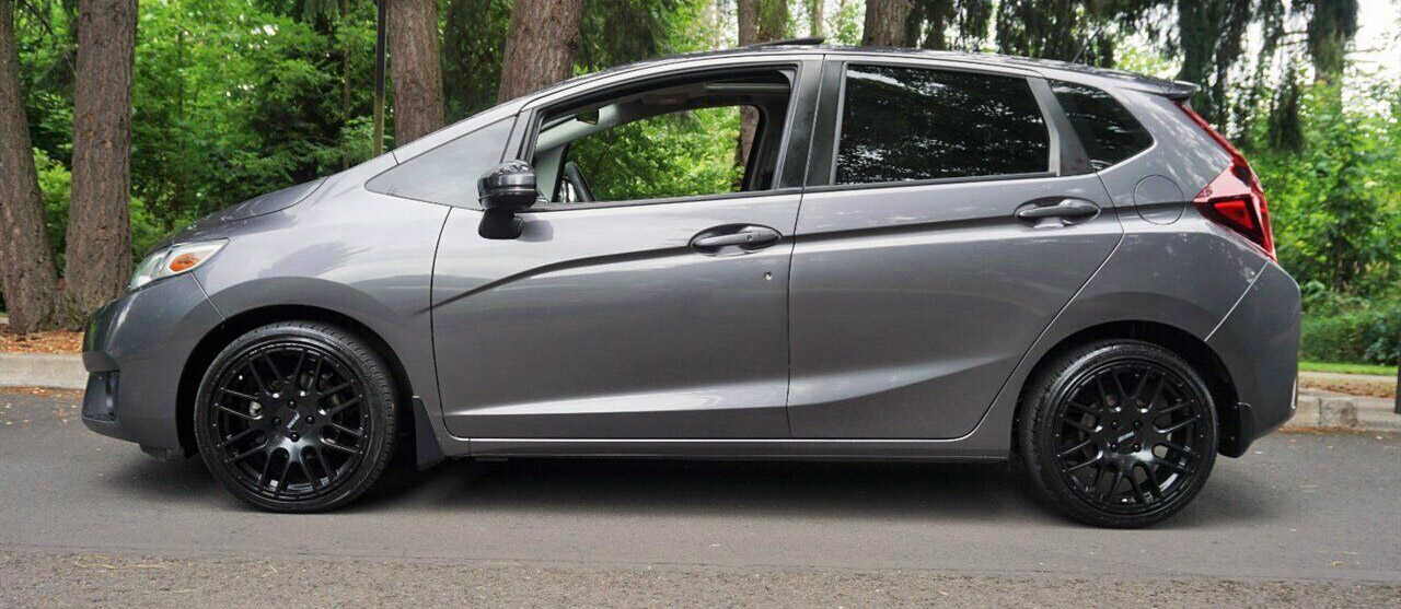 A grey car with precut window tints sitting in the street