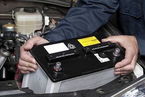 A mechanic changing a car battery with a memory saver