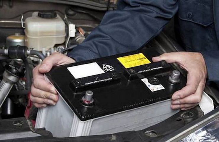 A mechanic changing a car battery with a memory saver