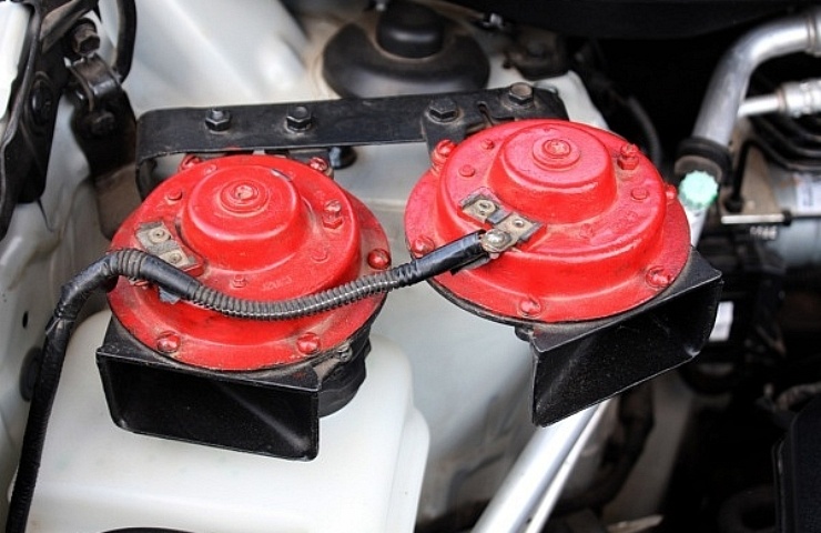 Dual red electric car horns mounted in an engine bay