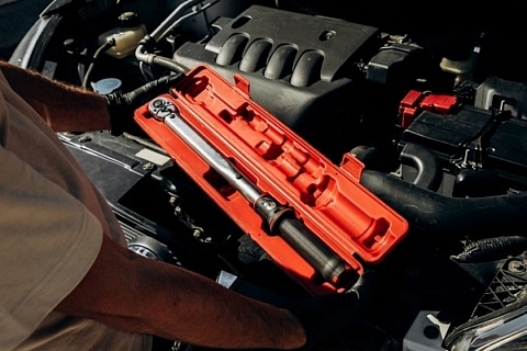Mechanic holding torque wrench in red storage box - featured