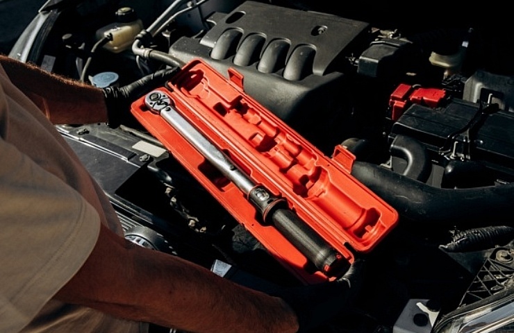 Mechanic holding torque wrench in red storage box - featured