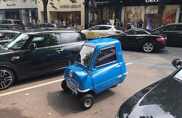 The Peel P50 sitting in a parking lot next to other cars