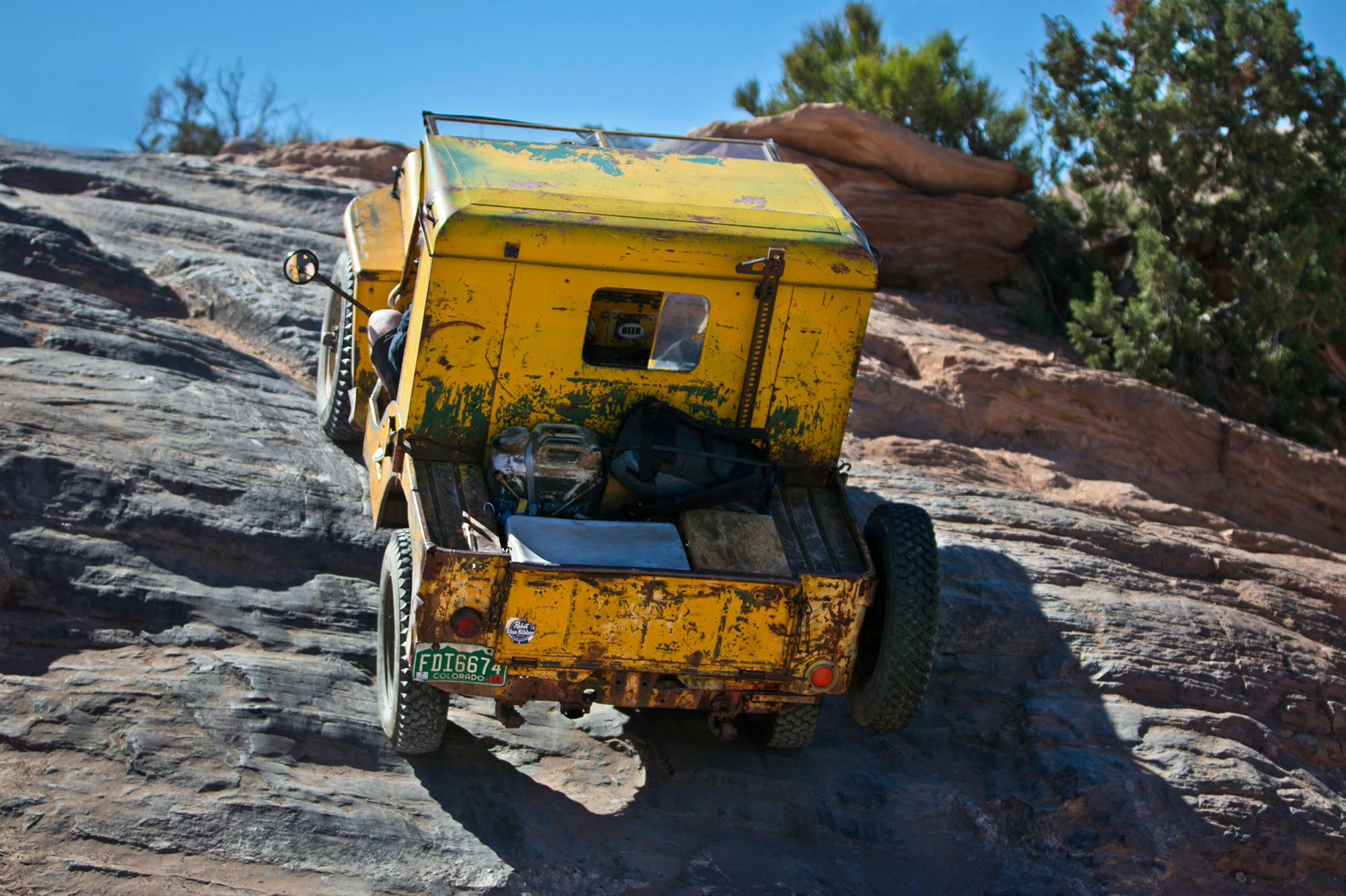 A tin-top flat fender Jeep steadily climbs the famous red rocks of Moab. (Photo by Mercedes Lilienthal, All rights reserved.)