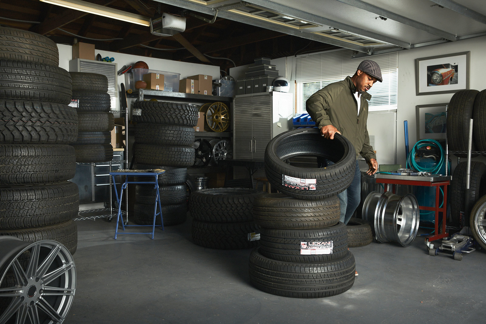 A man with stacks of tires in a garage