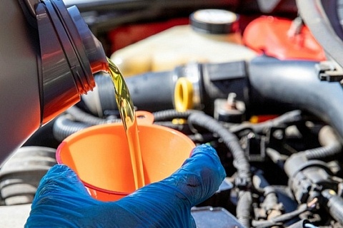 Pouring fresh oil into an engine with an orange funnel