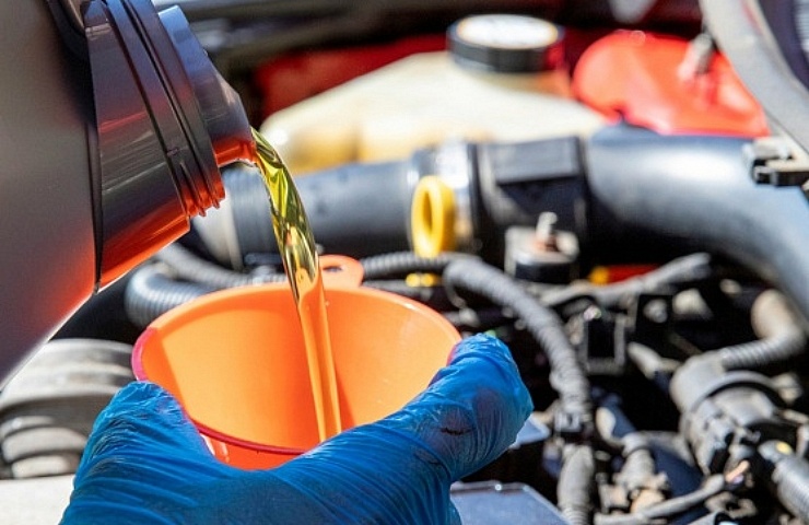Pouring fresh oil into an engine with an orange funnel