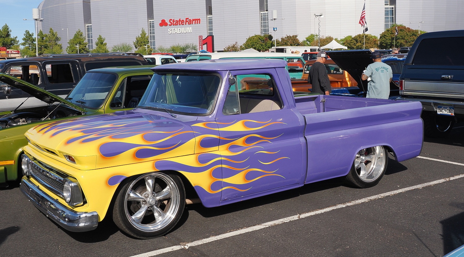 Purple Chevy truck with yellow flames in State Farm Stadium parking lot.