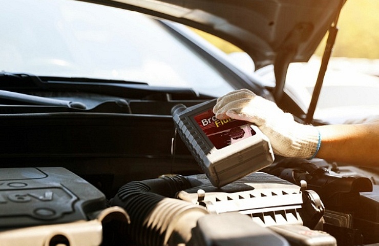 Car mechanic adding brake fluid in to the reservoir