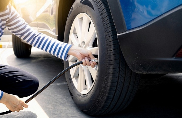 Woman checking tire pressure and inflating a car tire