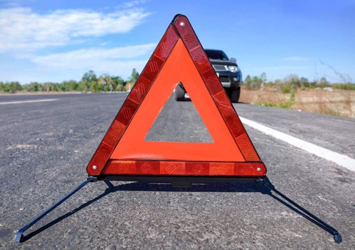 Reflective warning triangle on roadside, in front of parked vehicle