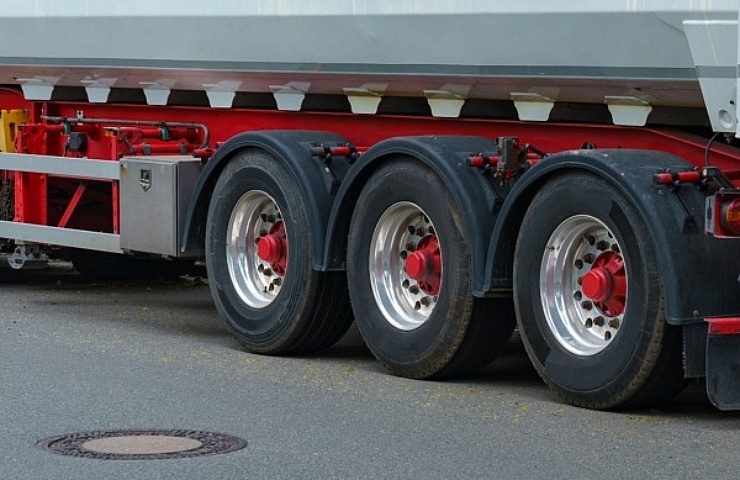 Three commercial truck tires on a bright red trailer with matching wheel accents.