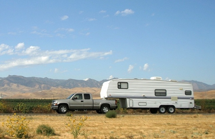 Pickup truck towing a travel trailer, with mountain range in the background