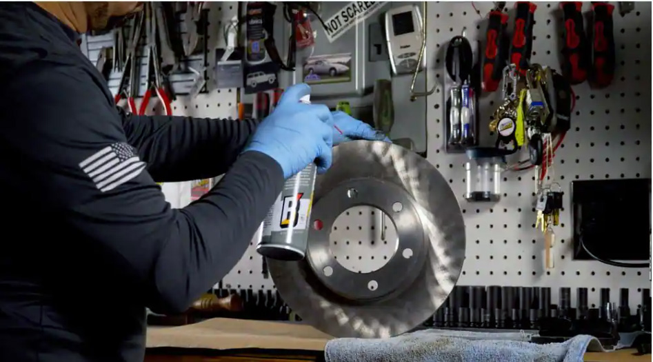 A man sprays brake cleaner on a brake rotor