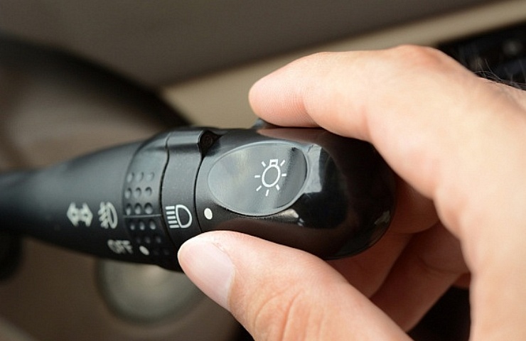 A hand adjusting the controls of a headlight switch