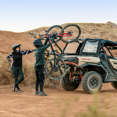 Two people loading two mountain bikes onto a Can-Am Commander XT UTV