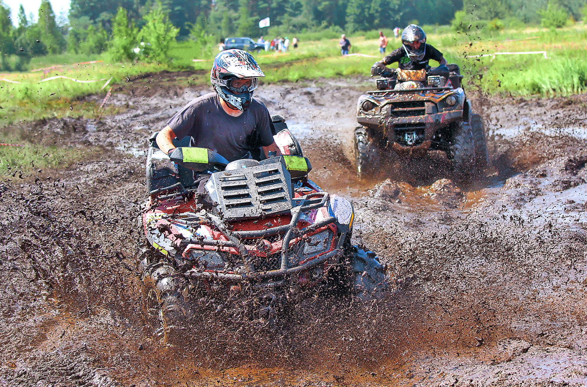 Two riders race ATVs in the mud