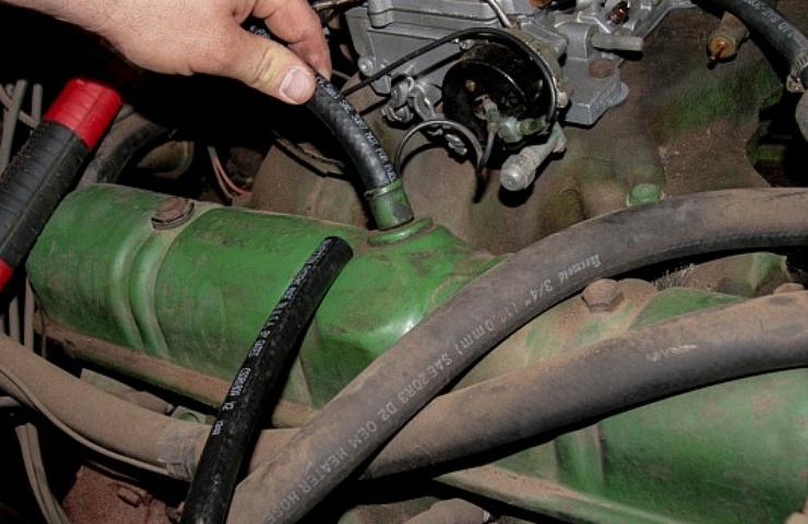 A man installing a Positive Crankcase Ventilation PCV valve on a 1963 Buick Nailhead V-8 engine