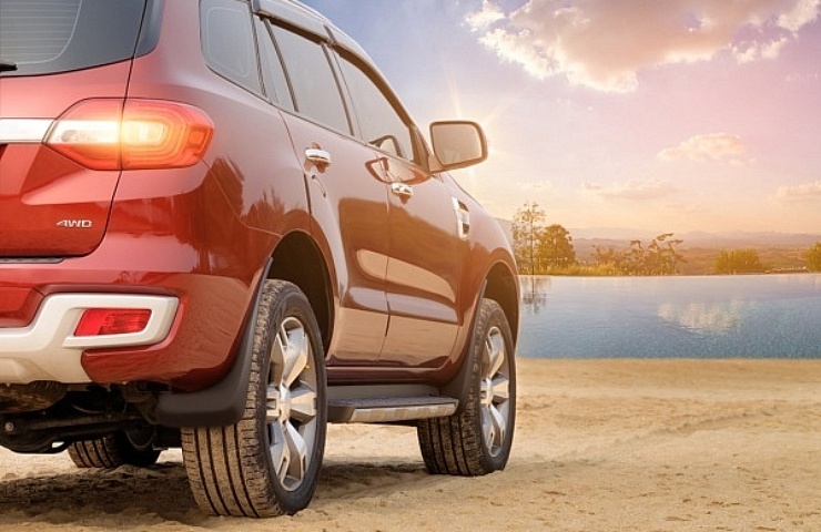 Red AWD SUV on a sandy beach at sunset - featured