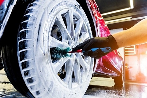 Cleaning a car wheel with a brush, soap, and water