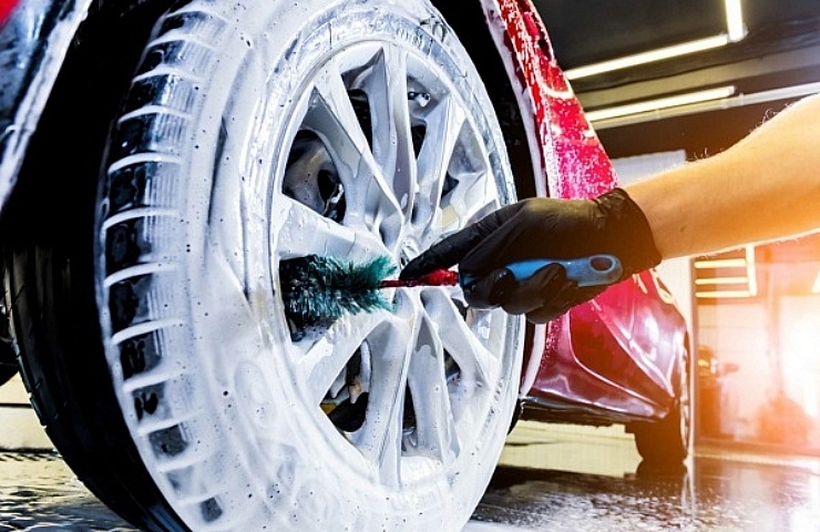 Cleaning a car wheel with a brush, soap, and water