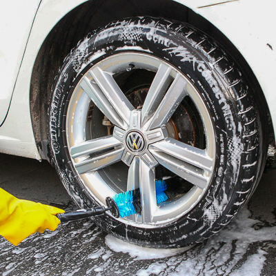 Using a bristle brush to clean a car wheel