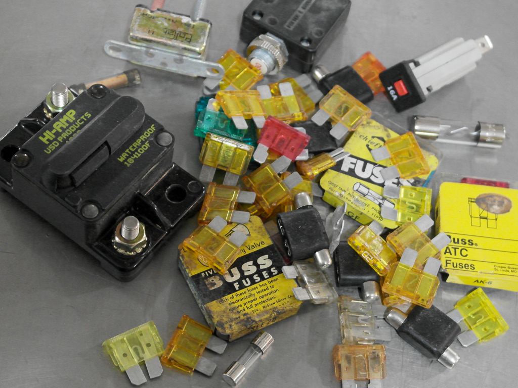 An assortment of different types of automotive fuses on a steel work bench table