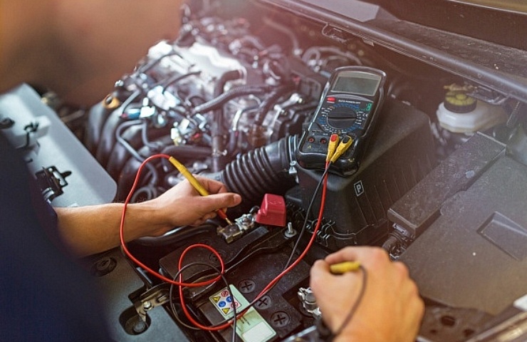 A mechanic checks a car's battery voltage