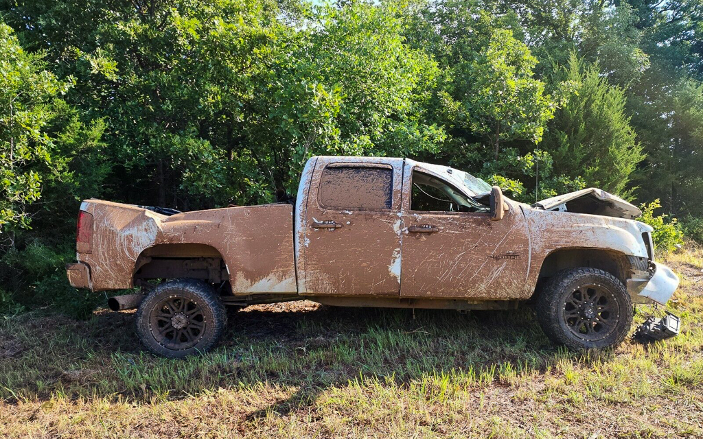 A rolled and mud covered wrecked pickup truck