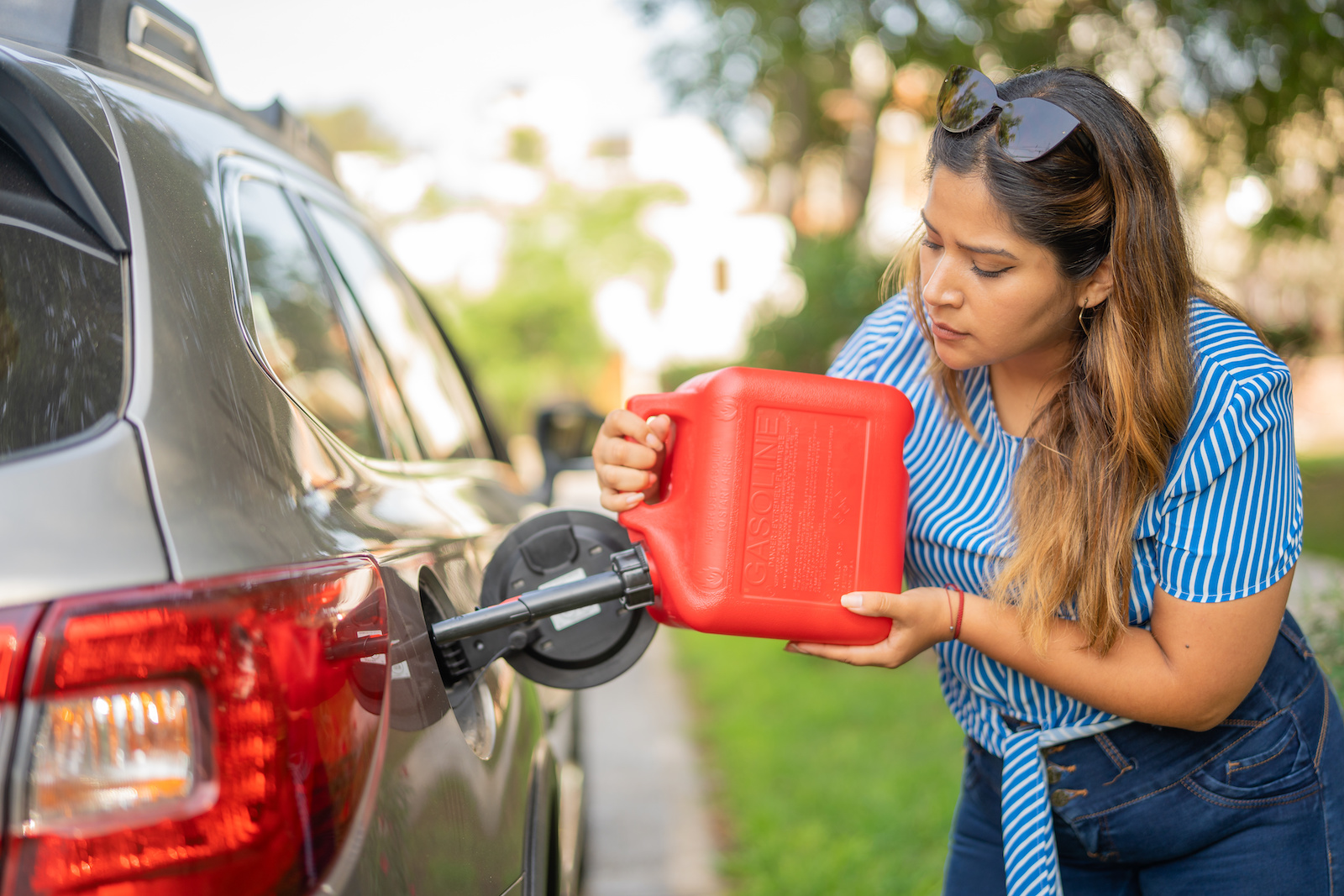 Woman putting gasoline in her car with a jerry can
