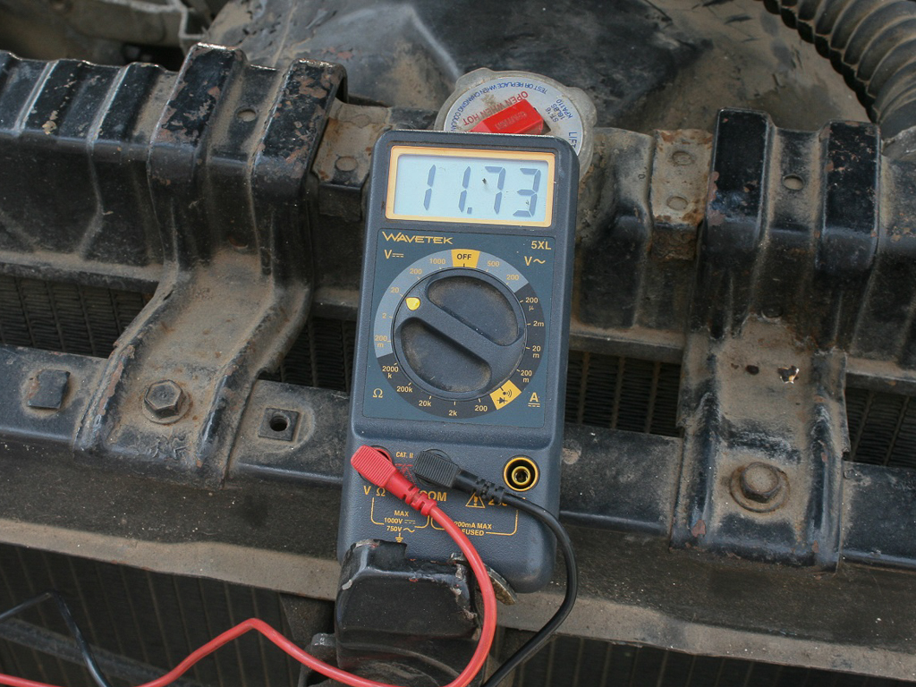 A digital multimeter in an engine bay. 