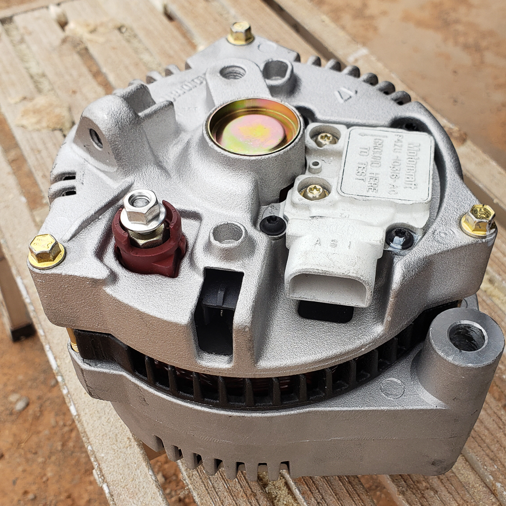 An alternator with an internal voltage regulator for a Ford on a bench. 