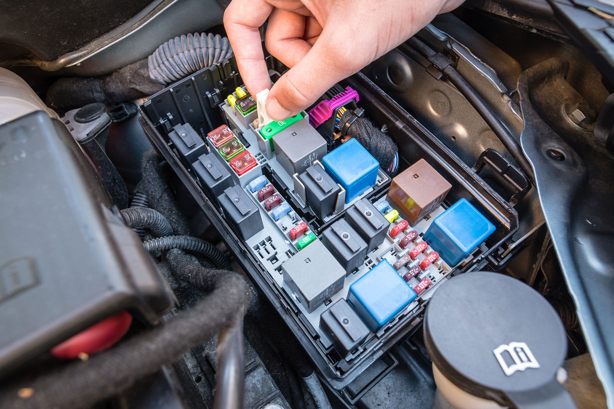 A driver checks a fuse in the fuse box of a modern car 