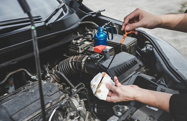 A driver checks engine oil level