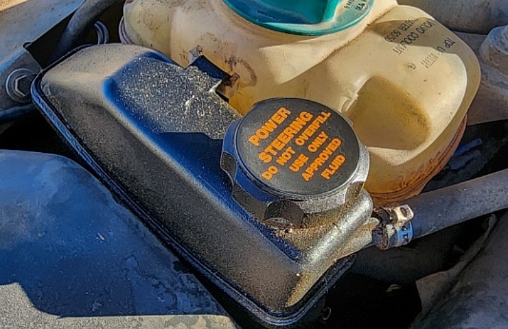 A power steering fluid reservoir and cap.