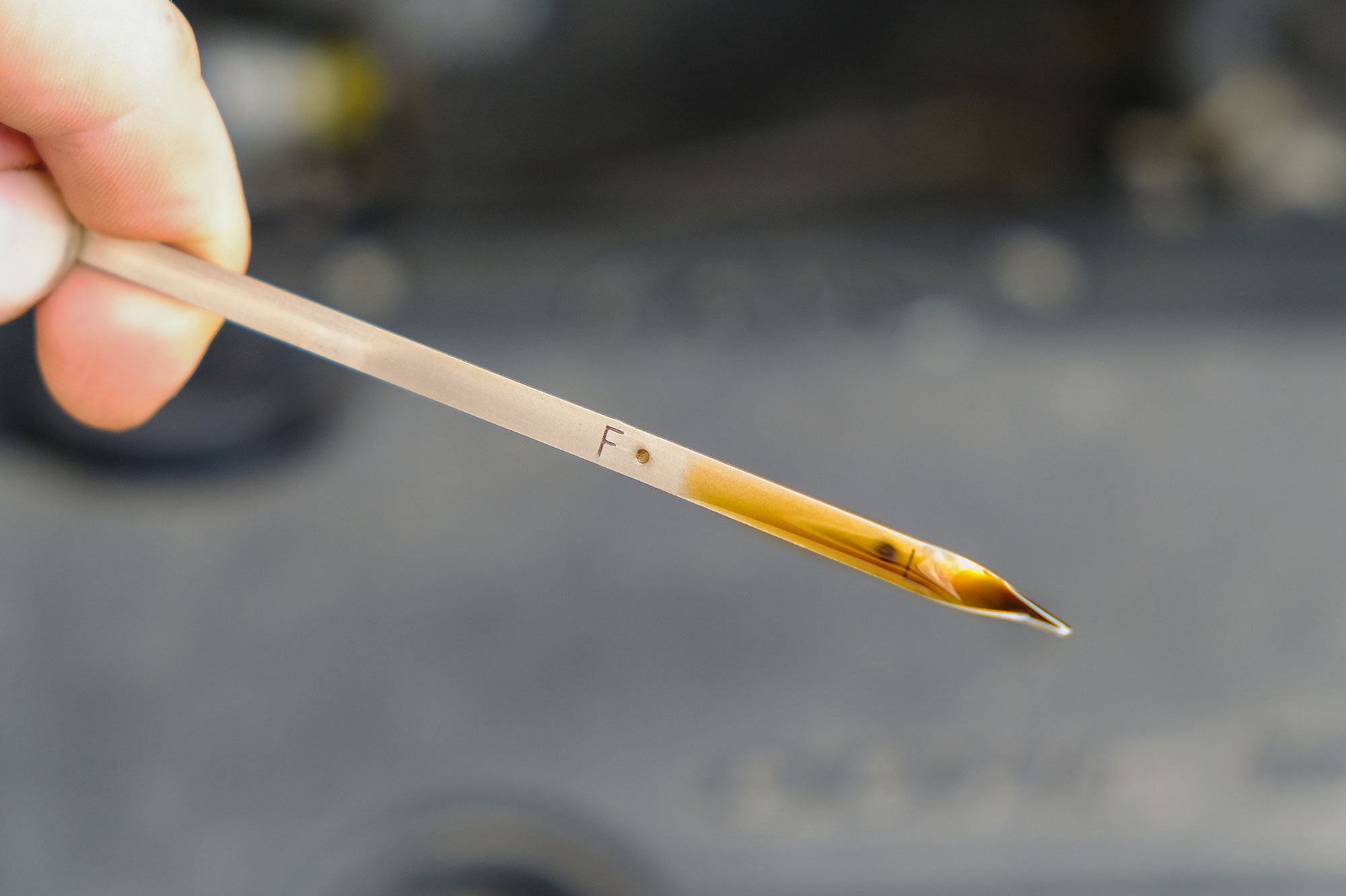 A car engine oil dipstick level marks.