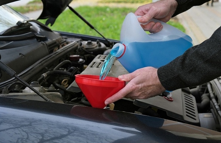 A driver pours windshield wiper fluid into his car