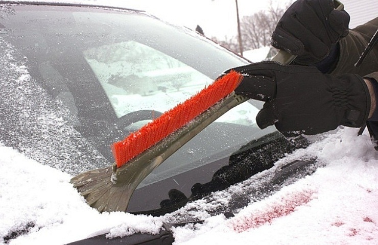 Defrosting windows starts with excess snow removal using a scraper brush