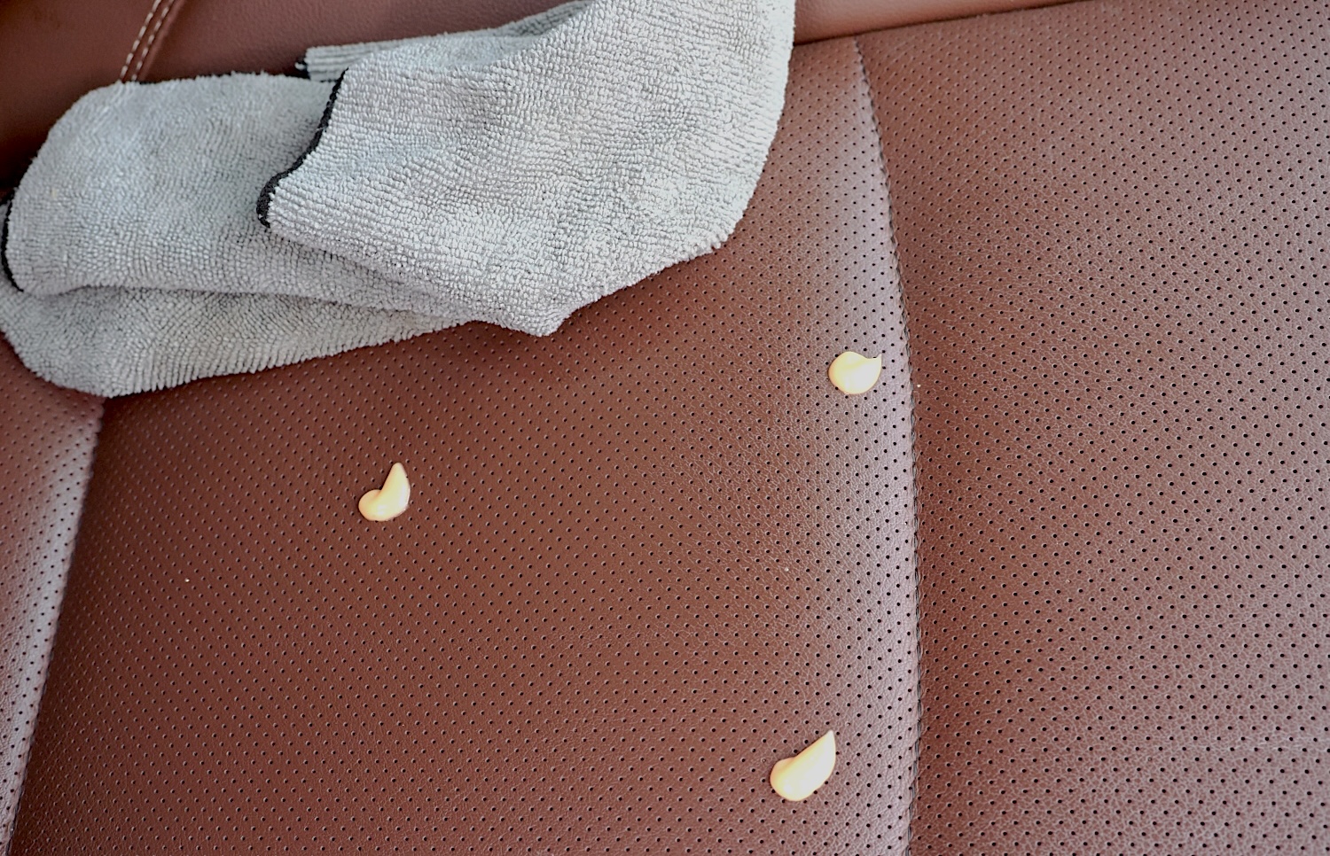 Cleaning car upholstery with leather cleaner and a microfiber towel