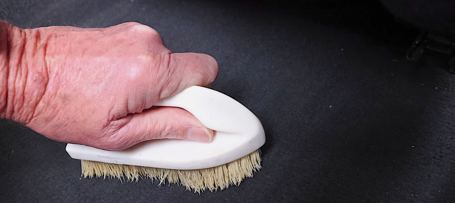 Cleaning car interior carpets with carpet cleaner and a stiff bristle brush
