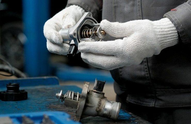 A mechanic inspects a new auto thermostat