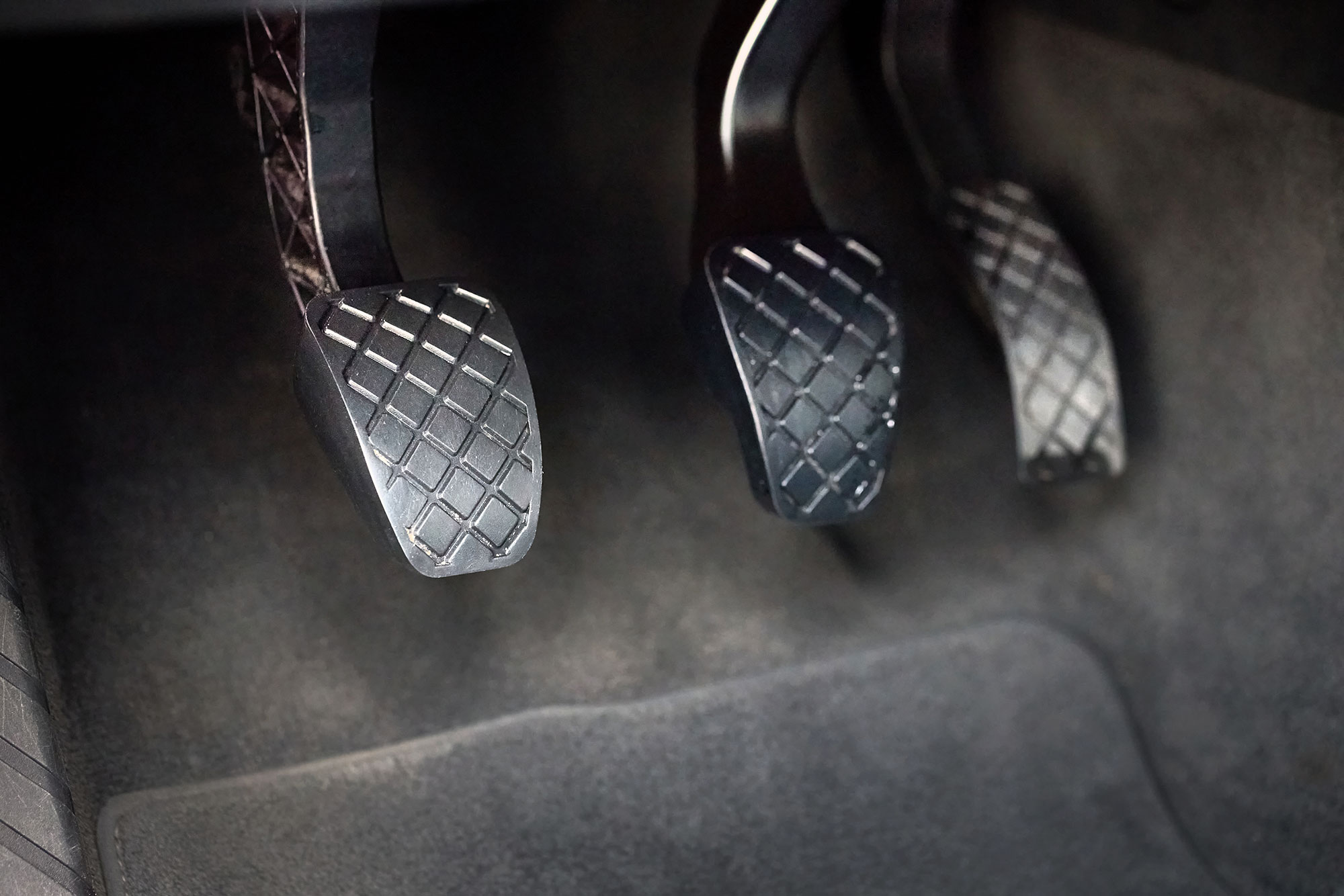 A manual transmission-equipped car's clutch pedal is at the far left 
