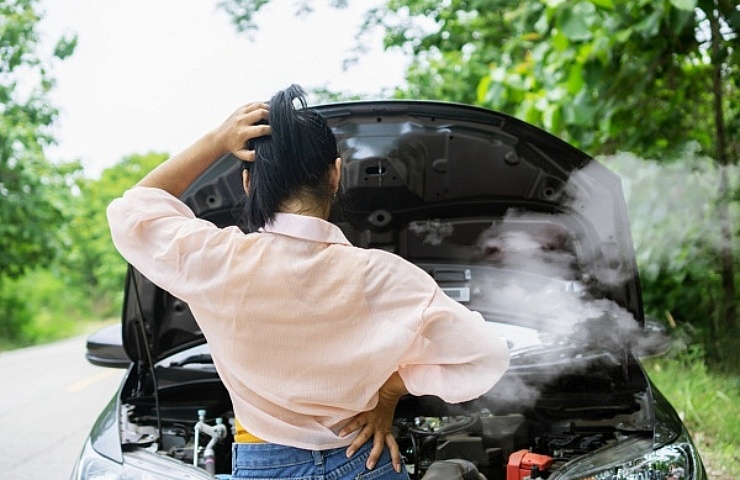 Woman having problem with overheated engine on the side of the road