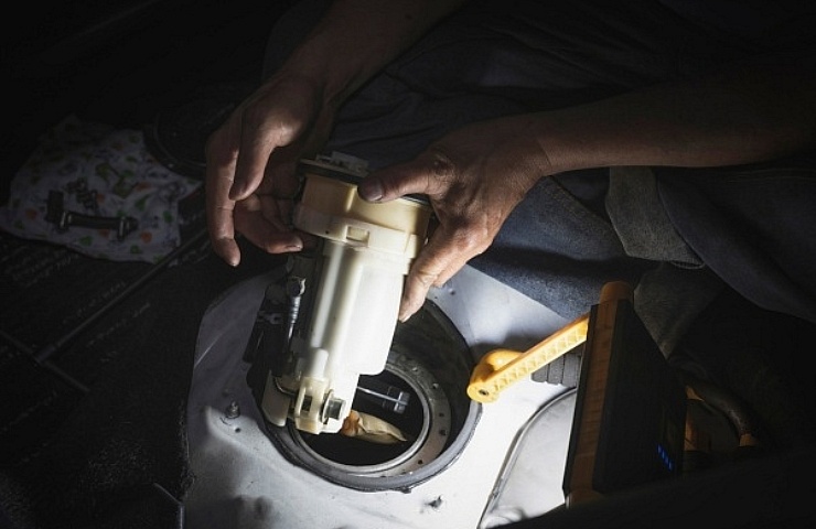 Mechanic installing electric in-tank fuel pump into a fuel tank.