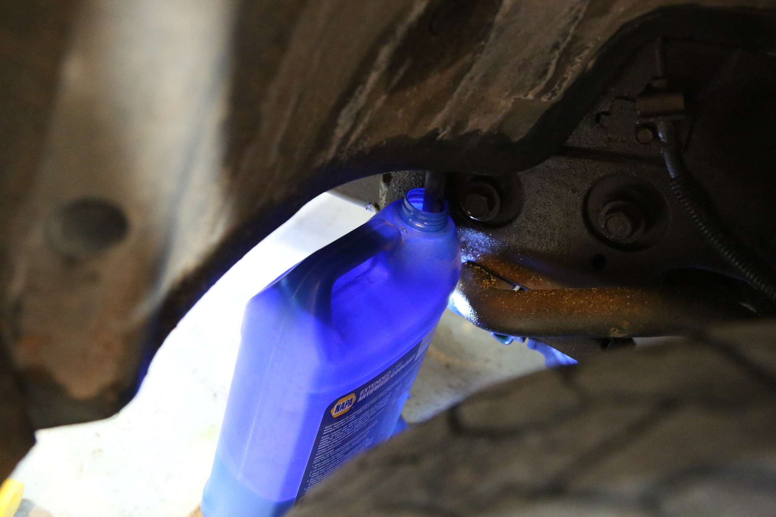 Using a hose to funnel coolant into a jug