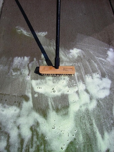 removing oil stains with a stiff-bristled scrub brush