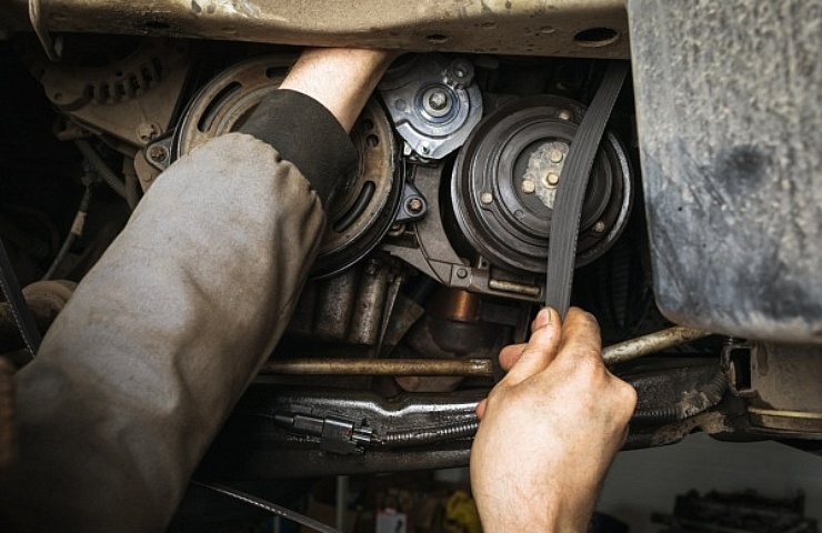 Mechanic replacing alternator belt - featured