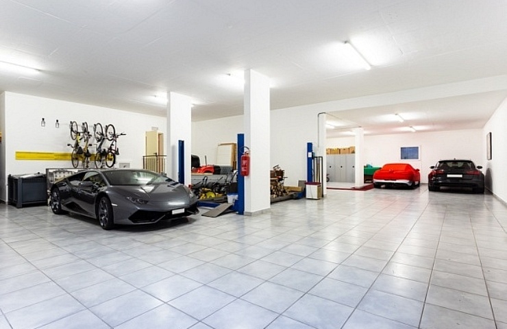 Large garage with a gray tile floor and three sports cars.