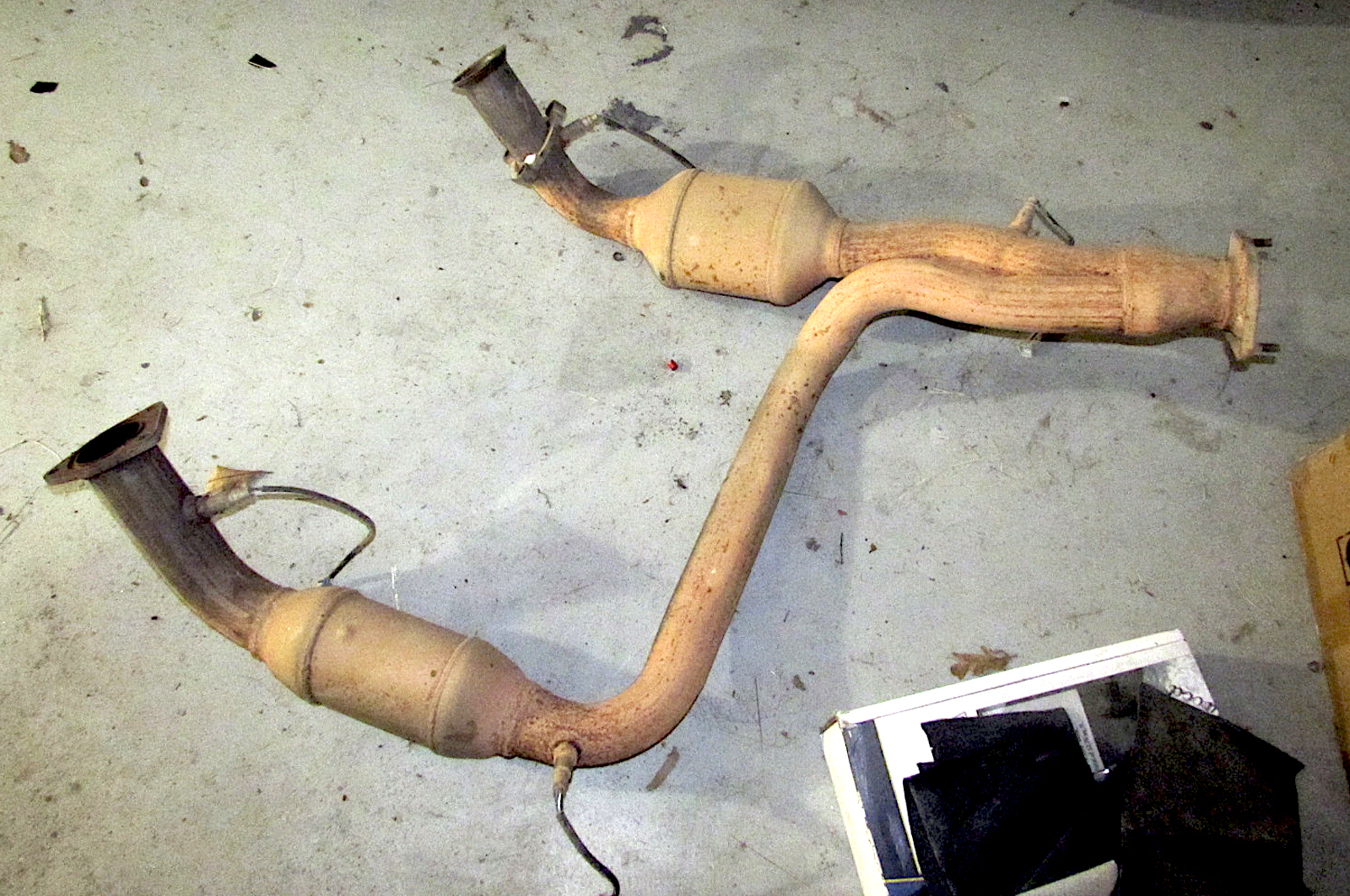 Exhaust system with dual catalytic converters on a concrete floor.