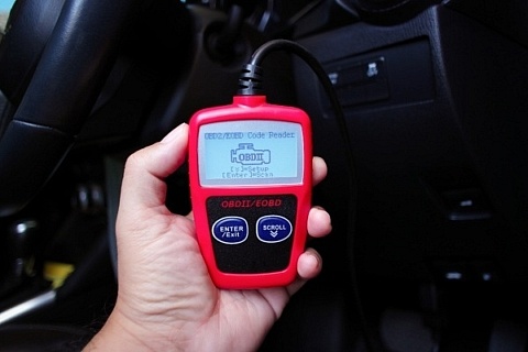 Vehicle owner holding a red OBDII scanner.
